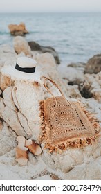 Straw Hat And A Woven Bag On A Rocky Beach Mobile Phone Wallpaper