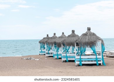 Straw huts with canopy beds on the beach with curtains, romantic summer holiday and honeymoon concept