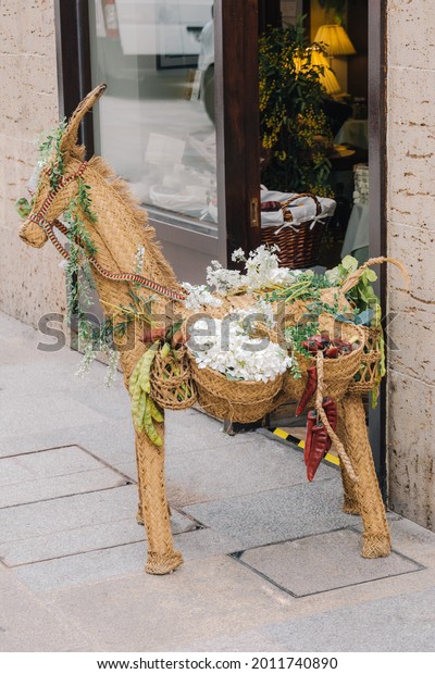 straw toy of an animal called llama with hanging\
saddlebags filled with vegetables and flowers as an ornament of a\
tent with selective focus