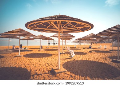 Straw Umbrellas On The Background Of The Lake Under A Cloudless Sky On A Hot Sunny Day.