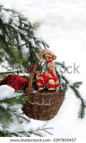 straw Yule Goat toy in wicker basket in snowy forest. Winter nature background. Yuletide, Christmas, New Year holidays. festive winter season. 