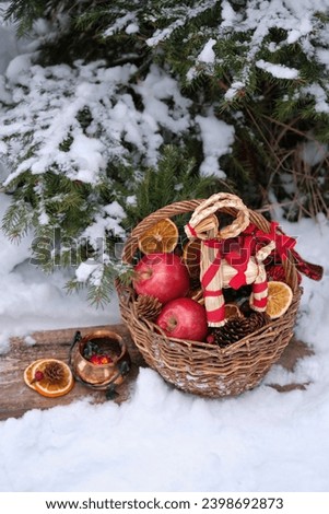 straw Yule Goat toy and wicker basket with apples and witch cauldron in snowy forest. Winter nature background. Yuletide, Christmas, New Year holidays. Magic ritual, witchcraft for winter solstice
