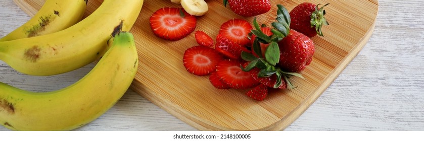 Strawberries And Bananas On Wooden Chopper Board