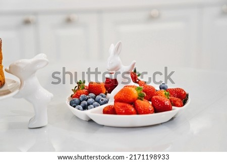 strawberries and blueberries in a white compartmental dish with rabbit. beautiful plate for appetizers, desserts and fruits. berries for the holiday and for every day. Stock photo © 