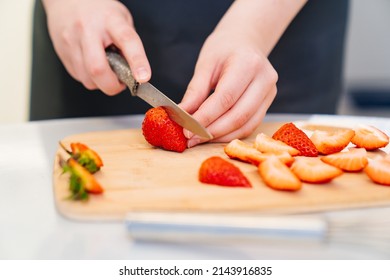 strawberries are cut into pieces on a wooden cutting board to decorate desserts. natural fresh fruits and berries for decorating cakes and cupcakes. recipes for cooking at home. chopped strawberries