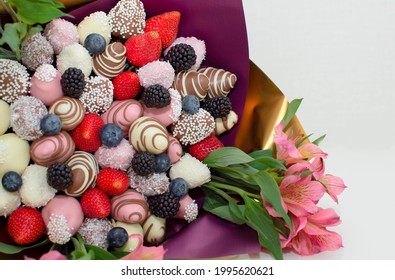 Strawberries in icing, covered with chocolate on a pink background, an edible bouquet, flowers. Strawberries dipped in dark and white chocolate in a bouquet.
