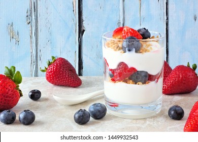 Strawberry And Blueberry Parfait In A Glass Against A Rustic Blue Wood Background