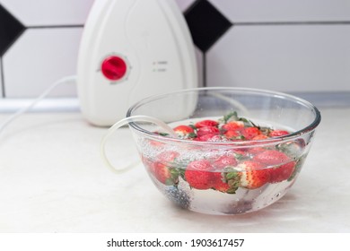 Strawberry In A Bowl With Water With A Round Ozonating Stone. Tubes Leading To Oxygen Pump And Ozone Generator. Ozonation Fruit. Food Disinfection With Ozon