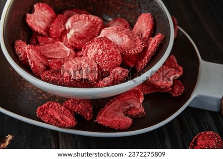 Strawberry chips are stacked in ceramic dish. Hundred-percent natural freeze-dried strawberries. Close up. Healthy vegetable chips