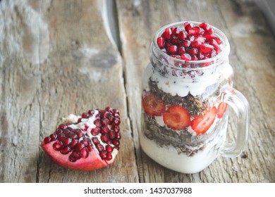 Strawberry Chocolate Granola Yogurt Parfait With Pomergranate In Mason Jar On The Old Wooden Board