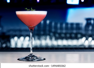 Strawberry cocktail on the bar counter. With background in shades of blue and blurred.