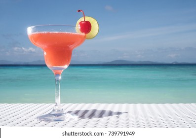 Strawberry Daiquiri cocktail on the white rattan table at the beach restaurant with beautiful blue sea and sky background