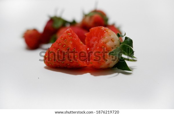 Strawberry is divided in half to see the\
importance of the inside, red ripe strawberries and a pile of\
strawberries in the\
background.