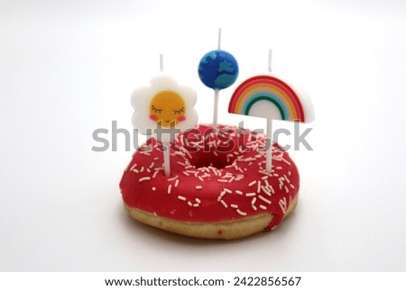 Strawberry donut with pink icing and springles and spring flower rainbow and earth day ecology space traveling on top snack and dessert foods on white background