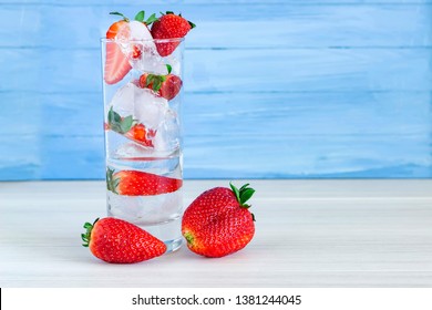 Strawberry In Font Of Cocktail With Ice On Blue Background With Strawberry On Top