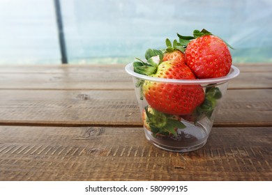 Strawberry fresh large size in a plastic glass on wooden floor in farm in South Korea