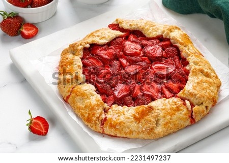 Strawberry galette. Open strawberry pie on marble board. Homemade pastry, baked cake with strawberry.