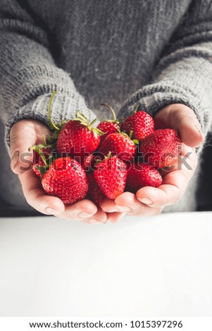 Strawberry in hand, hand holding strawberry, gray and white background