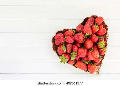 Strawberry heart. Fresh strawberries in plate on white wooden table. Top view, copy space.  