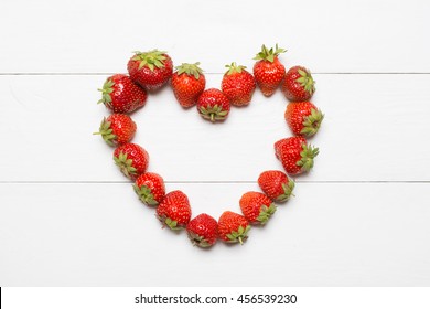 Strawberry heart on white wooden table concept