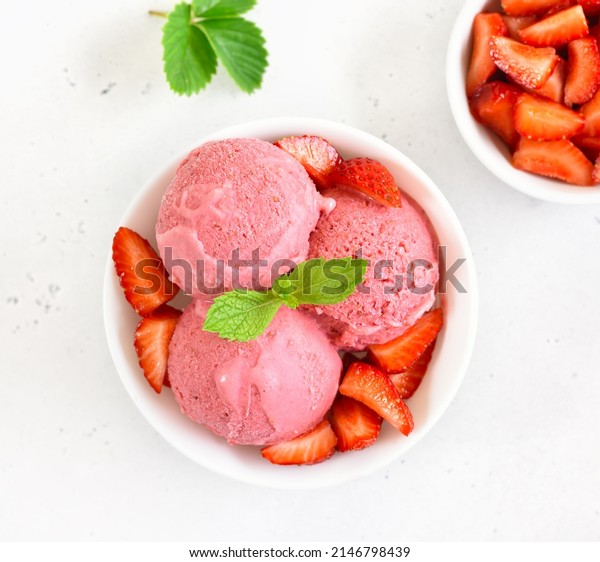 Strawberry ice cream in bowl on white stone\
background. Top view, flat\
lay