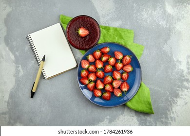 Strawberry Jam With Fresh Ripe Berries On Blue Plate, Blank Notepad With Copy Space And Pen. Recipe Book Mockup.