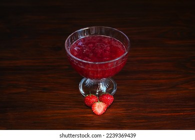 Strawberry jam in a wine glass, strawberries in the center, dark wooden table, space for text. Cut and whole berries, red crimson dessert in glass bowl, close-up, room for advertising text - Shutterstock ID 2239369439