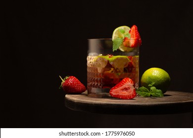 Strawberry And Lime Coktail In Crystal Glass With Ice Cubes And Mint Leaves On Wooden Table.Close Up.