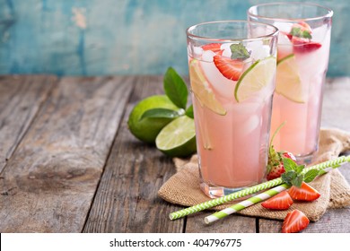 Strawberry and lime lemonade in tall glasses on wooden table