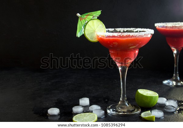 Strawberry Margarita or Daiquiri Cocktail with
lime on black background, copy space. Frozen homemade strawberry
summer cocktail.