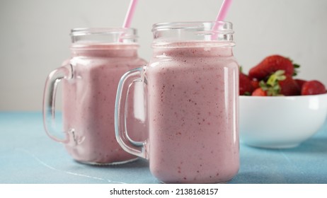 Strawberry milkshake in mason jars with fresh strawberries 
