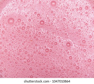 Strawberry milkshake texture. Pink bubbles of berry drink froth.Extreme close-up macro. Above view.