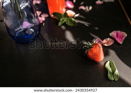 Strawberry with mint leaves on a black background. refreshing strawberry-infused vodka cocktail, complemented by peonies on a black backdrop. Burst of summer concept