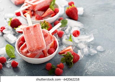 Strawberry and raspberry ice cream popsicles in white bowls