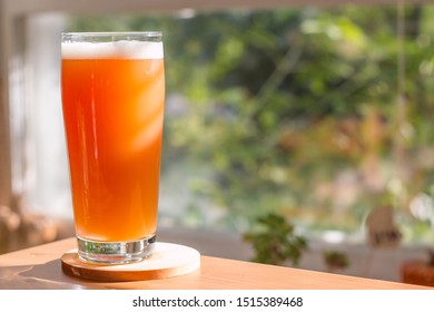 A Strawberry Rhubarb Cream Ale Craft Beer In A Pint Glass On A Kitchen Table In Sunlight.
