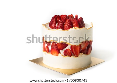 Strawberry shortcake decorated with butter cream and golden lines. Strawberry slices are layered in the middle part of the cake