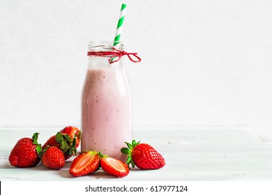 Strawberry smoothie or milkshake in a bottle with straw with fresh berries on white wooden background. healthy food for breakfast and snack