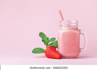 Smoothie de morango ou milkshake em jarra de pedreiro decorado hortelã na mesa rosa. Comida saudável para café da manhã e lanche.