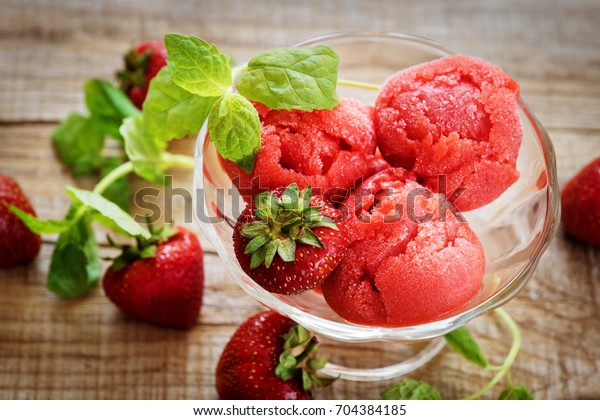 strawberry sorbet and\
sprigs of mint. in a bowl of ice cream and fresh strawberries on\
wooden background