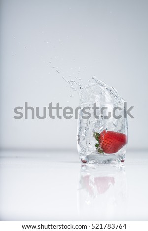 strawberry splash into water glass on white background
