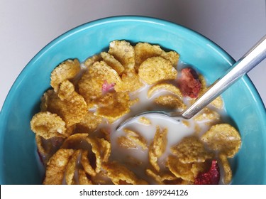 Strawberry, Sugary Cereal Bar With Milk. A Spoon, Yellow Yummy Corn, Oatmeal In The Blue, Turquoise Bowl For Breakfast. A Type Of American Healthy Breakfast.