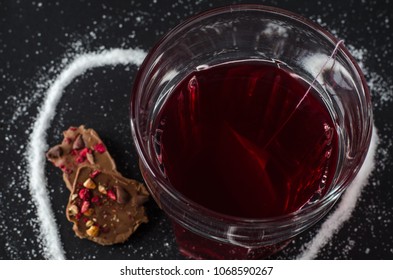 Strawberry Tea And Tea Bag In Glass, Spilled Sugar In Shape Of Heart Around, Berry Chocolate, On Dark Background