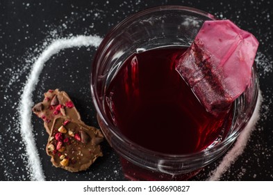 Strawberry Tea And Tea Bag In Glass, Spilled Sugar In Shape Of Heart Around, Berry Chocolate, On Dark Background