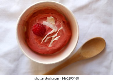 Strawberry vegan ice cream, decorated with raspberry and coconut flakes, in colorful paper cup. Top view. - Shutterstock ID 1460293460