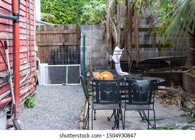 Stray Hungry Tabby Orange Ginger Cat With Sad Eyes Huddled On Cold Metal Table On Street Outside On House Home Patio In New Orleans, Louisiana