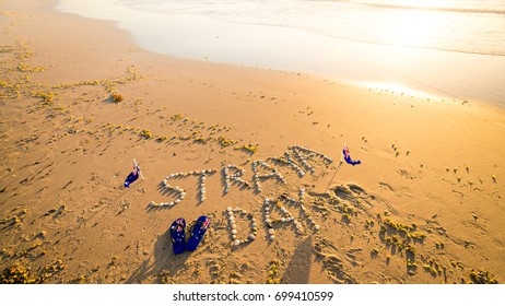 Straya text drawn using shells on sand with flags and thongs. Straya is an abbreviation of Australia