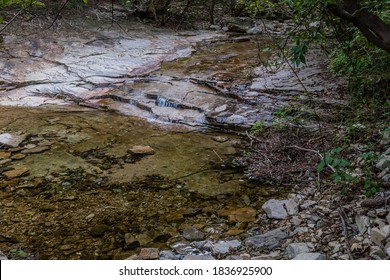 Stream Of Clean Clear Water Flowing Over Flat Rock Face Into Shallow Pool.