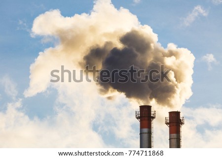Stream of dark smoke from the chimney of factory in the industrial district
