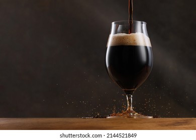 Stream Of Dark Stout Pours Into A Beer Glass. Detail Of Dark Beer With Overflowing Foam Head And Drips. Selective Focus	