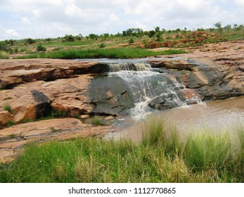 Stream flowing down flat rocks into muddy pond